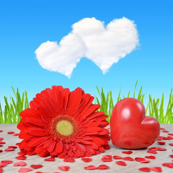 Red heart with gerbera flower on table. — Stock Photo, Image