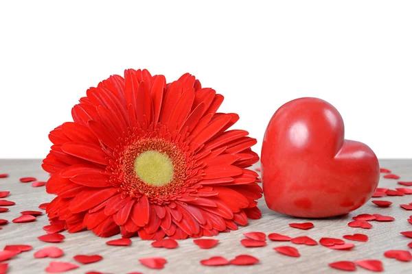 Red heart with gerbera flower on table. — Stock Photo, Image