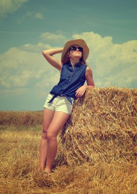 Bir balya saman üzerinde dinlenme şapkalı kadın