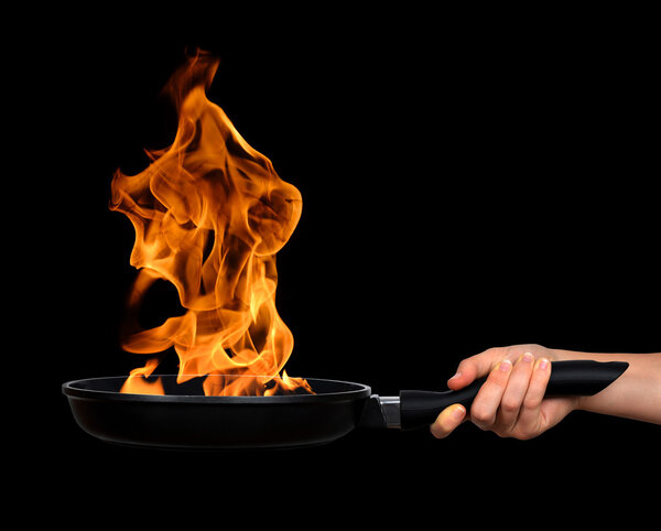 Woman's hand holding a frying pan with flames