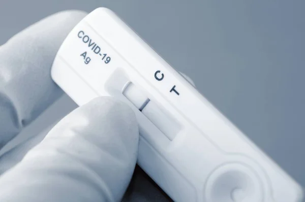 Hand in medical gloves is holding negative antigen rapid test for capturing of COVID-19 antibodies. It shows negative result.