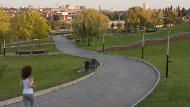 Жінка біжить в парку ввечері — стокове відео