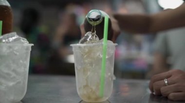 Lokantadaki paslanmaz çelik masada buzla dolu plastik bardaklara buzlu çay dök.