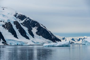 Antarktika Yarımadası 'nın engebeli dağlarının yatay olarak oluşturulmuş görüntüsü ve sudaki yansımaları. Danco Adası, Antarktika