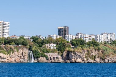 Antalya, Türkiye - 12 Ekim 2023. Antalya yakınlarındaki Akdeniz kıyısında modern yüksek binalarla çevrili bir şelale..