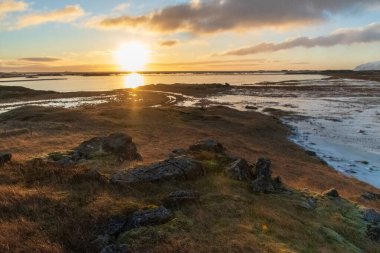 Alçak asılı, altın saat güneşi İzlanda 'nın güneydoğusundaki Cupivogur yakınlarında bir İzlanda manzarasını aydınlatıyor.