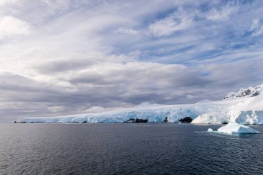Graham yakınlarındaki sakin bir Antarktika manzarası, Charlotte Körfezi boyunca uzanır, sert yansımaları, engebeli dağları ve etkileyici buzdağlarını vurgular..