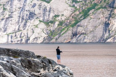 Bronnoy, Norveç - 25 Temmuz 2021. Norveç 'in orta kesimindeki bir gölde balık tutan bir kişiyi gösteren bir telefon..
