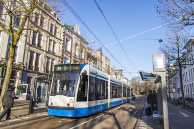 Amsterdam, Hollanda 1 Nisan 2016 üzerinde. Bahar sabahı tipik kent görünümünde. Tramvay caddeden aşağı taşır