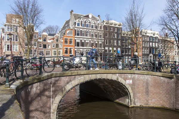 Amsterdam, Nizozemsko na 1 dubnu 2016. Typický městský pohled v jarní ráno. Most přes kanál a budovy stavby Xvii a Xviii na nábřežích — Stock fotografie