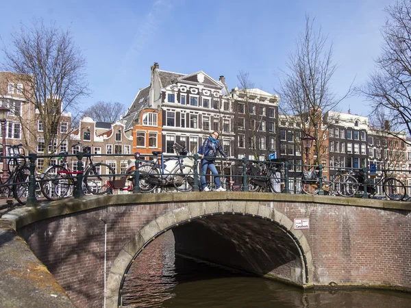 AMSTERDAM, NETHERLANDS on APRIL 1, 2016. Typical urban view in the spring morning. The bridge through the canal and buildings of the XVII-XVIII construction on embankments — Stock Photo, Image