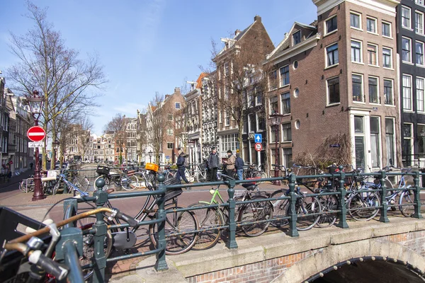 AMSTERDAM, PAÍSES BAJOS 1 DE ABRIL DE 2016. Típica vista urbana en la mañana de primavera. El puente a través del canal y los edificios de la construcción XVII-XVIII sobre terraplenes — Foto de Stock