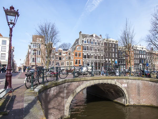 AMSTERDAM, NETHERLANDS on APRIL 1, 2016. Typical urban view in the spring morning. The bridge through the canal and buildings of the XVII-XVIII construction on embankments — Stock Photo, Image