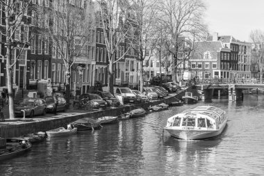 Amsterdam, Hollanda 1 Nisan 2016 üzerinde. Bahar sabahı tipik kent görünümünde. Kanal ve XVII-XVIII inşaat bentleri üzerinde binalar. Yürüyen gemi kanalda yüzen