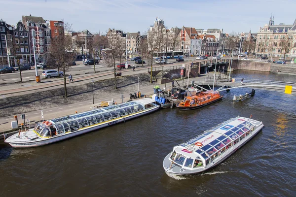 AMSTERDAM, PAESI BASSI il 1 APRILE 2016. Tipica vista urbana al mattino di primavera. Il canale e gli edifici della costruzione XVII-XVIII su argini. La nave che cammina galleggia sul canale — Foto Stock