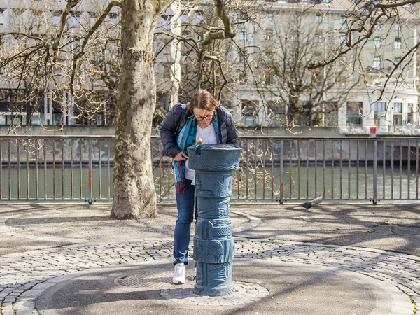 Zurich, Švýcarsko, na 26 březnu 2016. Jarní ráno. Žena pije vodu na ulici — Stock fotografie