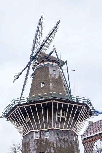 AMSTERDAM, PAÍSES BAJOS el 27 de marzo de 2016. Típica vista urbana en la mañana de primavera. Un antiguo molino en la orilla del río Amstel —  Fotos de Stock