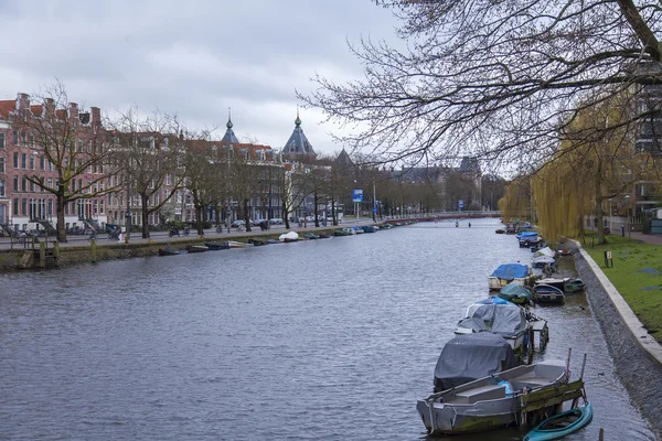 AMSTERDAM, NETHERLANDS on MARCH 27, 2016. Typical urban view in the spring morning. River Amstel. Architectural complex of the embankment. — Stock Photo, Image