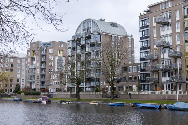 AMSTERDAM, NETHERLANDS on MARCH 27, 2016. Typical urban view in the spring morning. River Amstel. Architectural complex of the embankment. — Stock Photo, Image