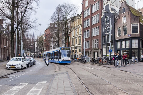 AMSTERDAM, PAÍSES BAJOS el 27 de marzo de 2016. Típica vista urbana en la mañana de primavera. El tranvía se mueve por la calle — Foto de Stock