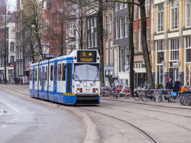 Amsterdam, Hollanda üzerinde 27 Mart 2016. Bahar sabahı tipik kent görünümünde. Tramvay caddeden aşağı taşır