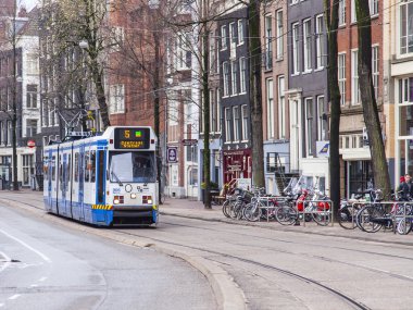 Amsterdam, Hollanda üzerinde 27 Mart 2016. Bahar sabahı tipik kent görünümünde. Tramvay caddeden aşağı taşır
