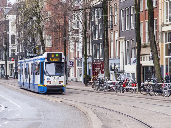Amsterdam, Hollanda üzerinde 27 Mart 2016. Bahar sabahı tipik kent görünümünde. Tramvay caddeden aşağı taşır