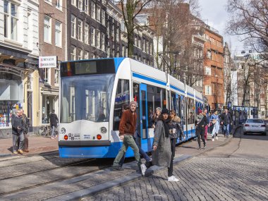 Amsterdam, Hollanda üzerinde 27 Mart 2016. Bahar sabahı tipik kent görünümünde. Tramvay caddeden aşağı taşır