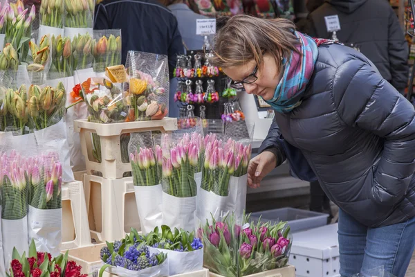 Amsterdam, Nederland op 27 maart. Verkoop van bloemen in de bloemenmarkt. Boeketten van verschillende tulpen. De vrouw koopt bloemen — Stockfoto