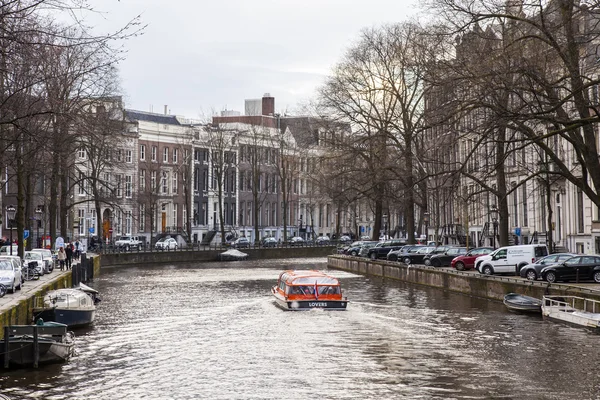 Amsterdam, Nederländerna den 27 mars, 2016. Typisk Urban utsikt under vår kvällen. Gång skeppet flyter på kanalen — Stockfoto