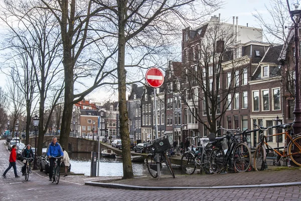 AMSTERDAM, PAÍSES BAJOS el 27 de marzo de 2016. Típica vista urbana en la noche de primavera. El puente a través del canal y los edificios de la construcción XVII-XVIII sobre terraplenes — Foto de Stock