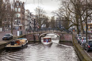 Amsterdam, Hollanda üzerinde 27 Mart 2016. Bahar akşam tipik kent görünümünde. Kanal ve Binalar bentleri tarihinde XVII-XVIII inşaatın Köprüsü