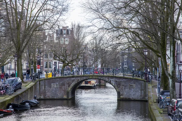 Amsterdam, Niederlande am 27. März 2016. Typische Stadtansichten am Frühlingsabend. die Brücke durch den Kanal und die Gebäude der xvii-xviii-Konstruktion auf den Dämmen — Stockfoto