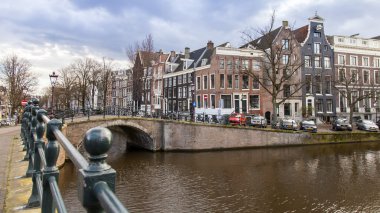 Amsterdam, Hollanda üzerinde 27 Mart 2016. Bahar akşam tipik kent görünümünde. Kanal ve Binalar bentleri tarihinde XVII-XVIII inşaatın Köprüsü