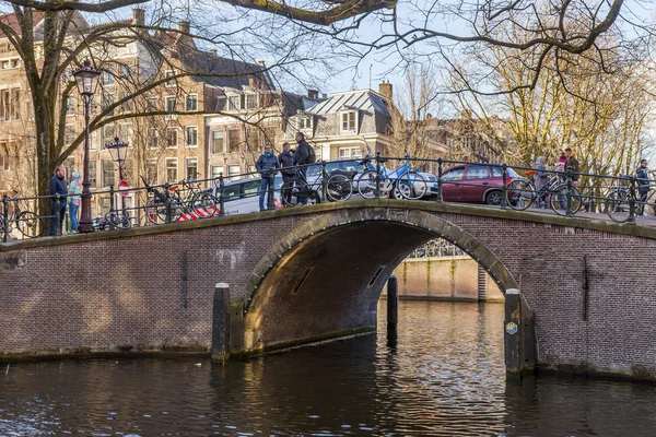 AMSTERDAM, NETHERLANDS on March 27, 2016. Типичный вид на город весной. Мост через канал и здания XVII-XVIII вв. — стоковое фото