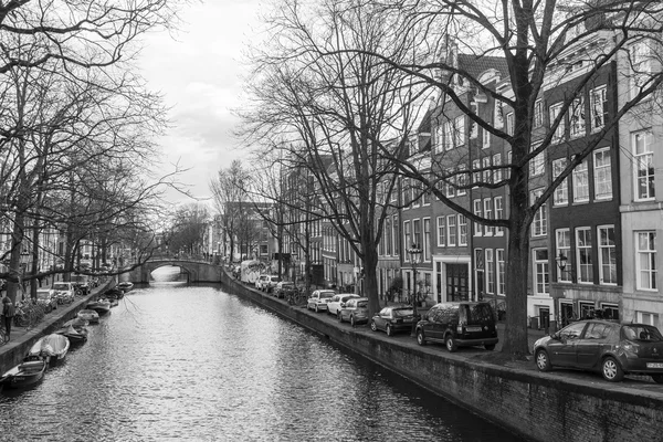 AMSTERDAM, PAÍSES BAJOS el 27 de marzo de 2016. Típica vista urbana en la noche de primavera. El puente a través del canal y los edificios de la construcción XVII-XVIII sobre terraplenes — Foto de Stock