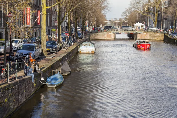 Amsterdam, Niederlande am 27. März 2016. Typische Stadtansichten am Frühlingsabend. die Brücke durch den Kanal und die Gebäude der xvii-xviii-Konstruktion auf den Dämmen — Stockfoto