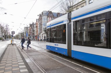Amsterdam, Hollanda üzerinde 28 Mart 2016. Bahar öğleden sonra tipik kent görünümünde. Tramvay caddeden aşağı taşır. 