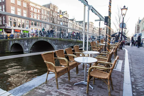 Amsterdam, Niederlande am 28. März 2016. Typische Stadtansichten am Frühlingsabend. Kleine Tische im Sommercafé unter freiem Himmel. — Stockfoto