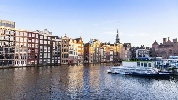 AMSTERDAM, NETHERLANDS on MARCH 27, 2016. Typical urban view in the spring evening. The bridge through the canal and buildings of the XVII-XVIII construction on embankments — Stock Photo, Image