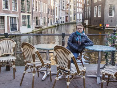 Amsterdam, Hollanda üzerinde 28 Mart 2016. Bahar akşam tipik kent görünümünde. Küçük tablolar yaz Kafe'nin kaldırımda. Kadın bir dinlenme bir tablo vardır.
