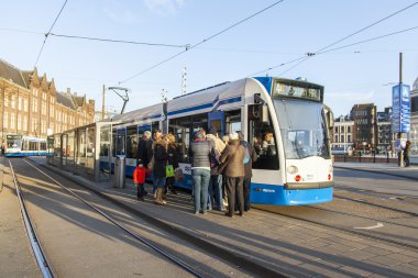 Amsterdam, Hollanda üzerinde 28 Mart 2016. Bahar öğleden sonra tipik kent görünümünde. Tramvay caddeden aşağı taşır. 