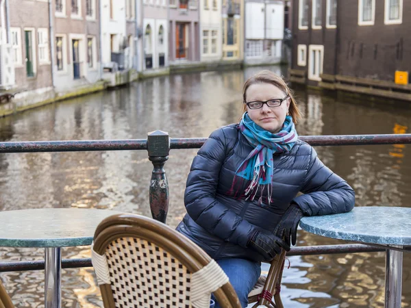 Amsterdam, Hollanda üzerinde 28 Mart 2016. Bahar akşam tipik kent görünümünde. Küçük tablolar yaz Kafe'nin kaldırımda. Kadın bir dinlenme bir tablo vardır.