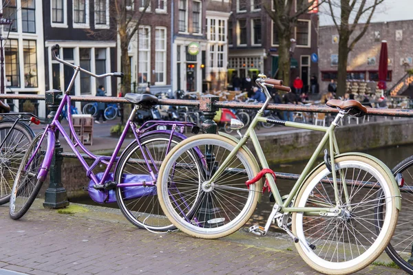 Amsterdam, Nederländerna på 27 mars 2016. Stadslandskapet. Cyklar är parkerade på bron via kanalen — Stockfoto