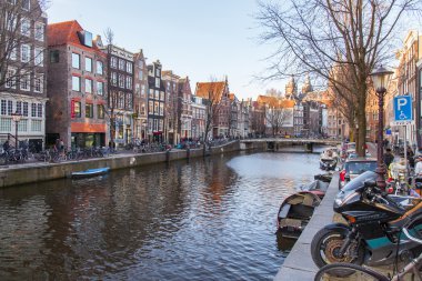 Amsterdam, Hollanda üzerinde 28 Mart 2016. Bahar öğleden sonra tipik kent görünümünde. Kanal ve XVII-XVIII inşaat bentleri üzerinde binalar. Yürüyen gemi kanalda yüzen