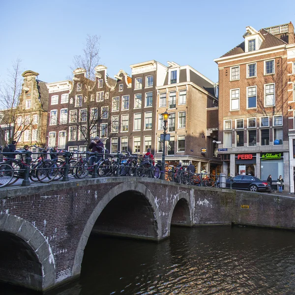 AMSTERDAM, PAÍSES BAJOS 28 DE MARZO DE 2016. Típica vista urbana en la tarde de primavera. El canal y los edificios de la construcción XVII-XVIII sobre terraplenes. El barco a pie flota en el canal — Foto de Stock