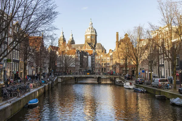 AMSTERDAM, NETHERLANDS on March 28, 2016. Типичный вид на город весной. Канал и здания XVII-XVIII вв. постройки на набережных. Ходячий корабль плавает по каналу — стоковое фото