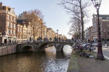 Amsterdam, Hollanda üzerinde 28 Mart 2016. Bahar öğleden sonra tipik kent görünümünde. Kanal ve XVII-XVIII inşaat bentleri üzerinde binalar. Yürüyen gemi kanalda yüzen