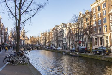 Amsterdam, Hollanda üzerinde 28 Mart 2016. Bahar öğleden sonra tipik kent görünümünde. Kanal ve XVII-XVIII inşaat bentleri üzerinde binalar. Yürüyen gemi kanalda yüzen