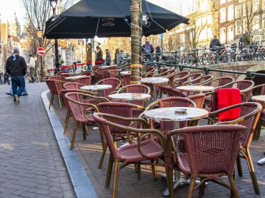 Amsterdam, Hollanda üzerinde 28 Mart 2016. Bahar akşam tipik kent görünümünde. Yaz Kafe'nin kaldırımda küçük tablolar.